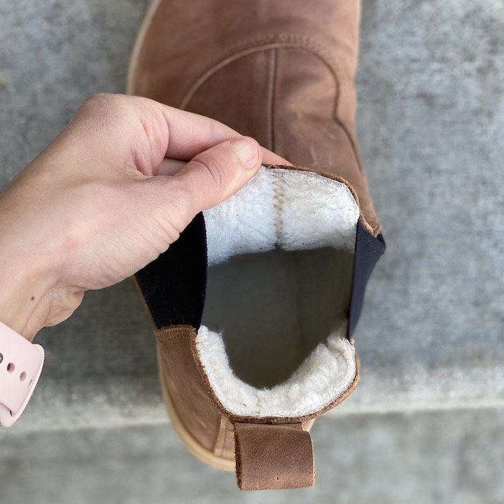 A hand holding open the top edge of Angles Fashion barefoot boots to show the thermal synthetic lining.