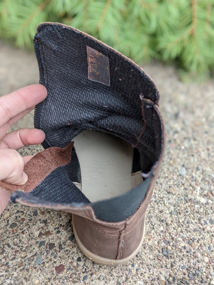 A hand holding open an Angles Fashion Dafne barefoot boot to show the interior lining