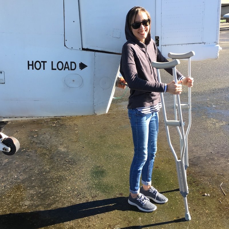 Anya, the barefoot shoe queen, standing outside using crutches because she had such bad foot pain before switching to barefoot shoes