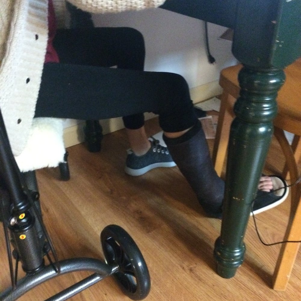 Anya sitting at a table wearing a cast on her right foot because of severe foot pain