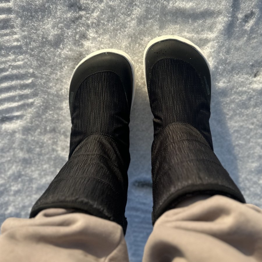 A pair of warm winter barefoot boots with a wide toe box standing on freshly fallen snow. Barebarics Polar Stride insulated barefoot winter boots are being worn with cozy sweatpants outside in the elements
