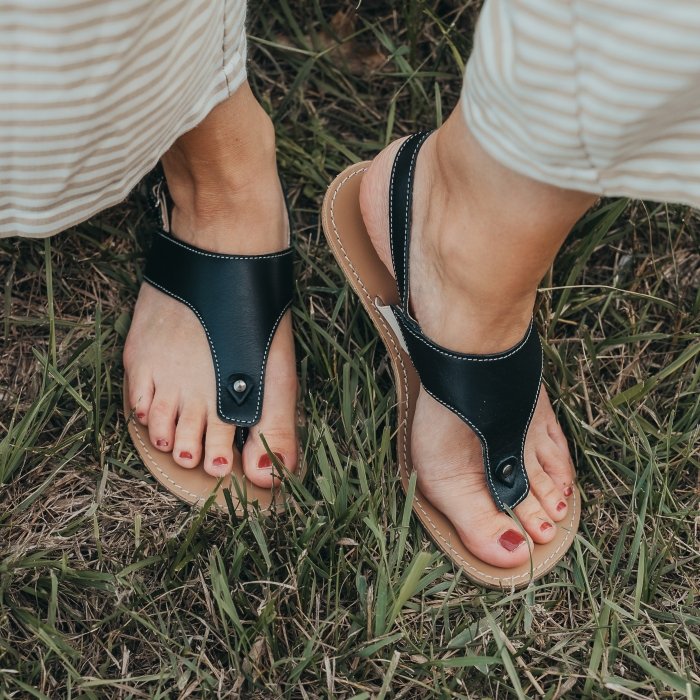 A person's feet in Be Lenka Promenade in black leather worn with beige striped flowy pants.