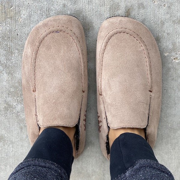A top down view of a pair of feet wearing Bearfoot Shoes Osos barefoot slip-on shoes in tan color