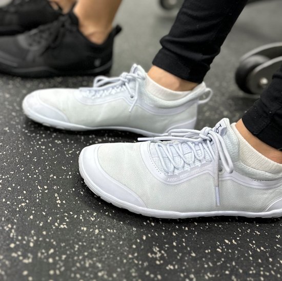 A close up side view of a woman's feet in Tolos archetype 2.0 in white, barefoot sneakers for gym training