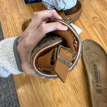 A hand holding a Birkenstock Lutry clog into a tight roll to show the flexibility without the birkenstock insole