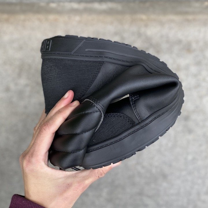 A hand holding one Birkenstock QS 700 safety shoe into a U shape to show flexibility.
