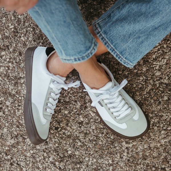 A close up of a pair of crossed feet wearing Bohempia Felix, a vegan barefoot sneaker with a wide toe box