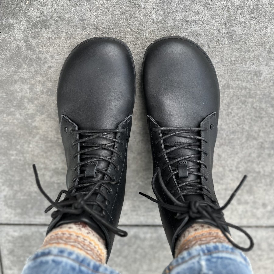 Top down view of Xero Shoes Breckenridge black leather lace ups shoes being worn on cement. The wide toe box leaves room for natural toe splay