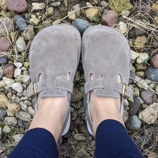 Top down view of a pair of wide feet wearing Butterfly Your World barefoot clogs on colorful rocks