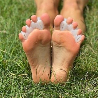 A person wearing Correct Toes anatomical spacers showing the soles of their feet