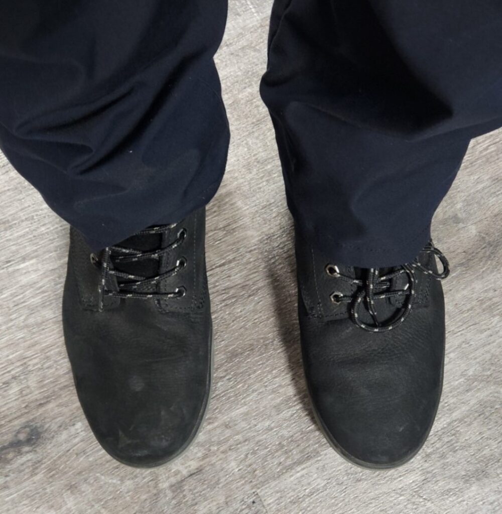 Top down view of a person in work pants wearing black leather DeWalt Plasma steel toe zero drop safety boots