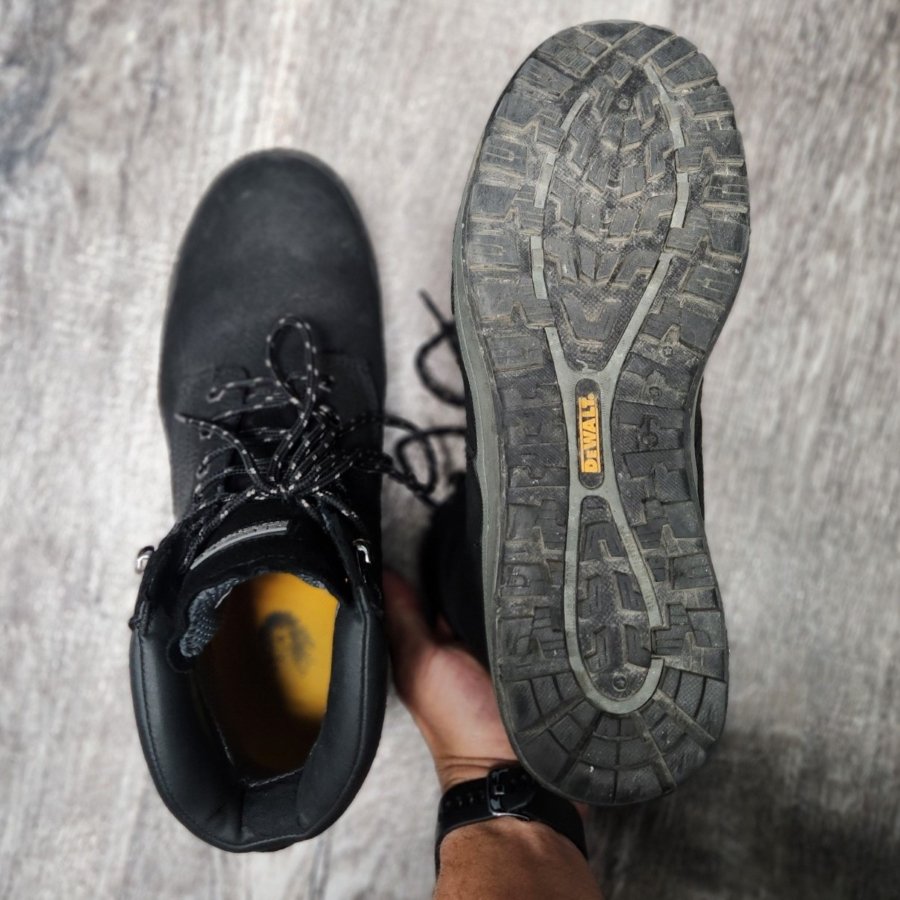 A pair of DeWalt Plasma steel toe boots off the foot, with 1 shoe upside down to show the outsole tread and shape. They have a wider than average toe box and soft leather uppers