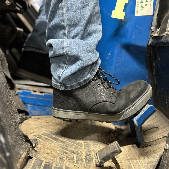 DeWalt Plasma Steel Toe zero drop safety boot being worn while driving a tractor. The foot is pressing on the pedal and flexing