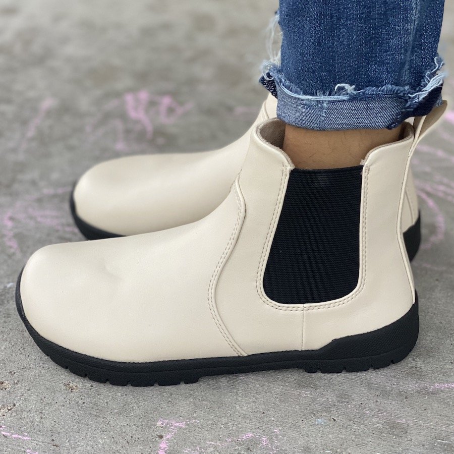 a close up a pair of feet standing on concrete wearing feelgrounds chelsea barefoot boots in white vegan leather fall winter