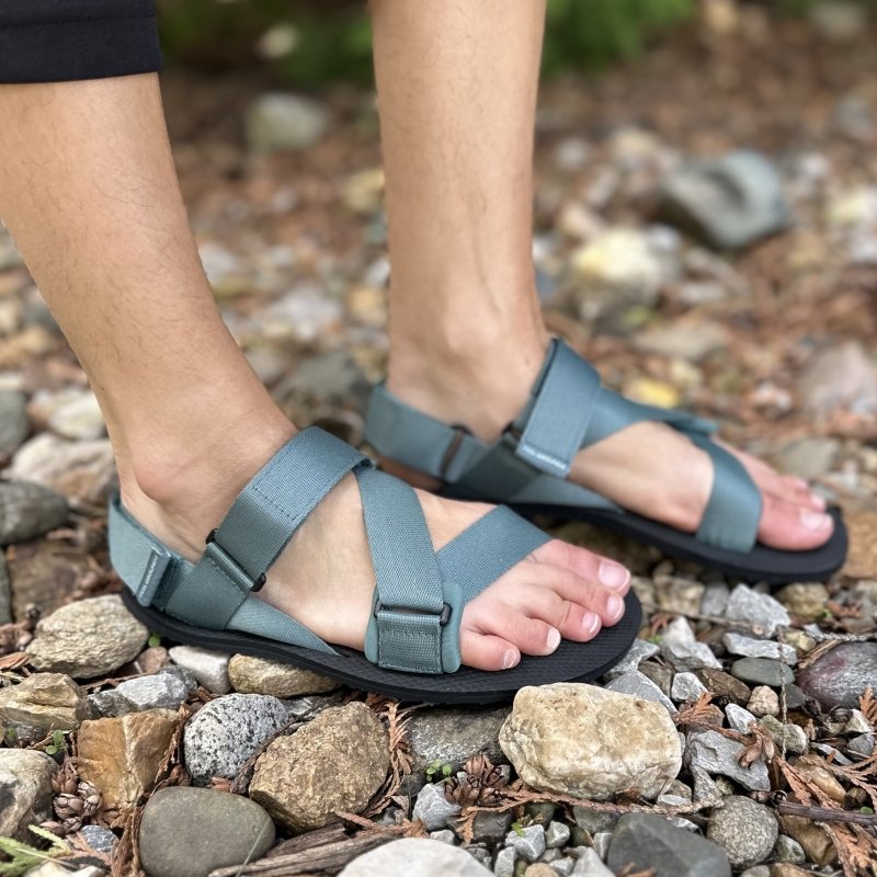 Side view of a person wearing Feelgrounds vegan Pathways sandals on rocky ground