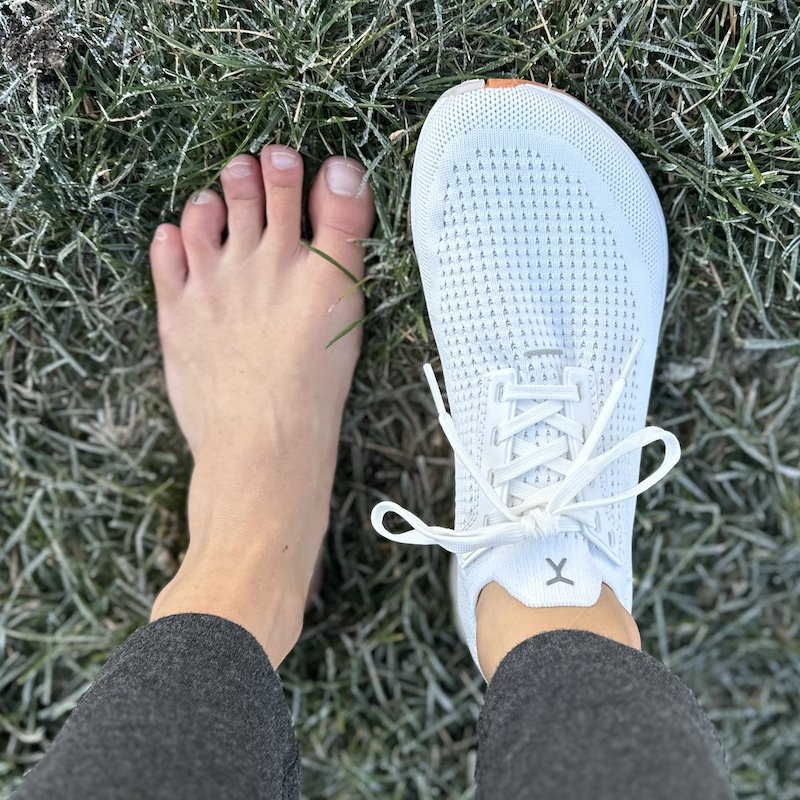 Top down view of a person's wide feet wearing 1 Topo Athletic running shoe. You can see the anatomical toe box shape compared to the bare foot