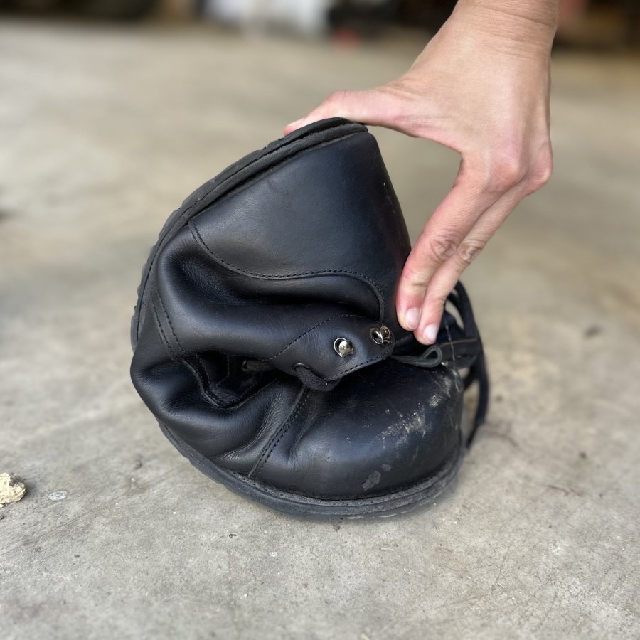 A hand squishing a Gaucho Ninja Carpenter's Steel Toe safety boot into a C shape to show flexibility