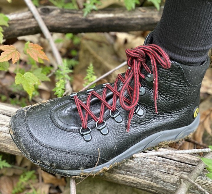 Close up of Joe Nimble 2.0 zero drop hiking boot in the wild stepping on a log with mud around the sole