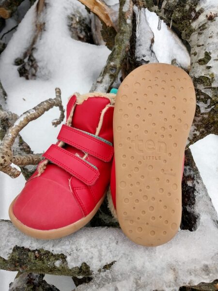 Red sneakers from Ten Little sitting on icy branches. One shoe is showing the rubber sole