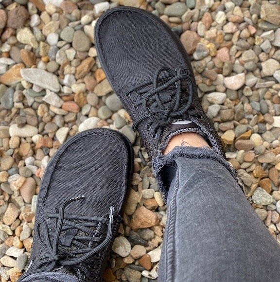 A pair of Lems barefoot boulder boots shown from the top, worn by a woman standing on colorful rocks