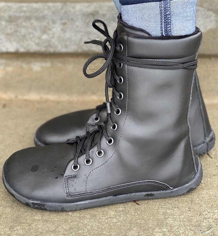 A close up side view of a pair of Ahinsa Jaya Vegan barefoot flexible combat boots. The ties are doubled wrapped around the top of the boots.