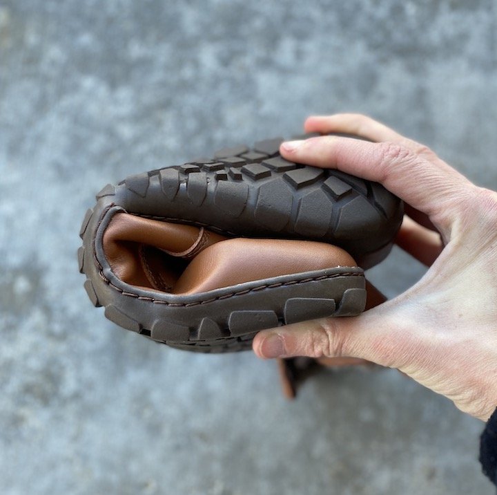 A close up of a handing folding a Zaqq Vegan winter boot into a squished U shape to show flexibility.