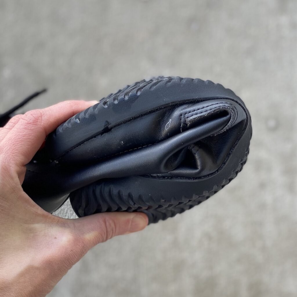 A woman's hand holding a Ahinsa Jaya boot into a flat U shape to show the flexibility.