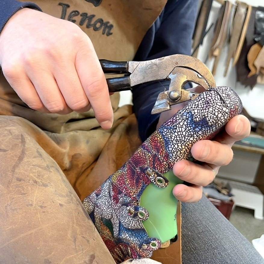 Close up view of a pair of hands using a tool to stretch the leather around a modified last for custom production of J Joplin ballet pumps from Jenon Leather