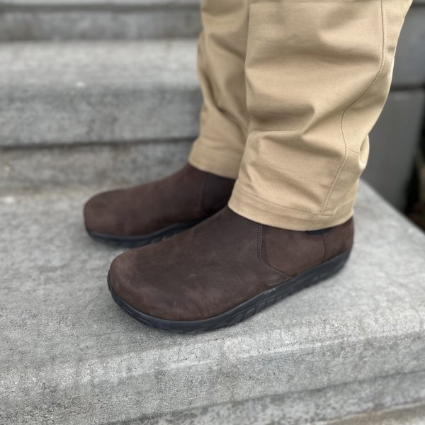 Close up side view of a man's legs in khaki dress pants. He is wearing Lems Chelsea boots on his feet, a wide toe box zero drop dressy boot