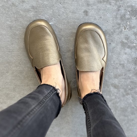 Top down view of Lisbeth Joe London barefoot women's dress loafers in gold leather being worn with black skinny jeans