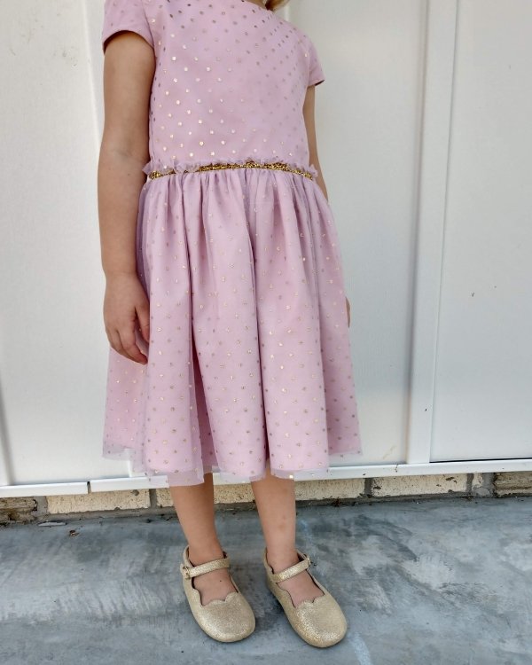 A young child in a frilly pink dress wearing glittery ballet flats from Little Love Bug, which offers fancy barefoot shoes for littles