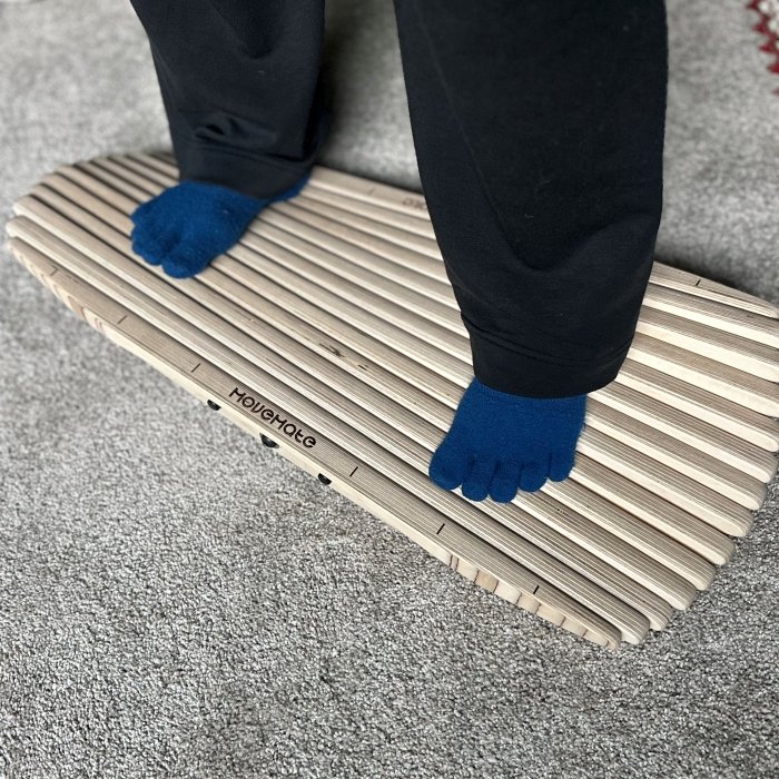 A pair of toe socked feet standing on a Movemate active standing wiggle board