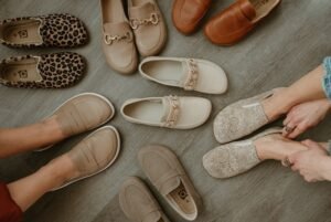 A collection of wide toe box barefoot loafers in neutral colors, prints, and stylish designs scattered around