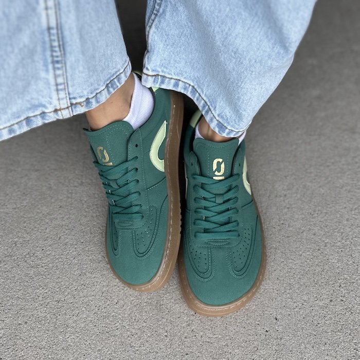 A top down view of a pair of feet wearing Ohne Project Retro barefoto sneaker 070 model, dark green vegan suede with lime green accents