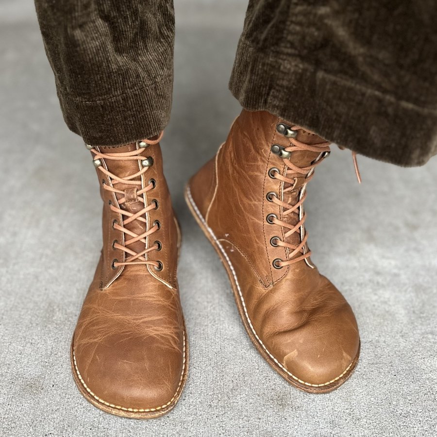 Front and side flexed view of Origo Adventurer barefoot lace up leather boots with wide toe box and flexible zero drop sole. Brown wide leg corduroy pants are visible on top of the boots
