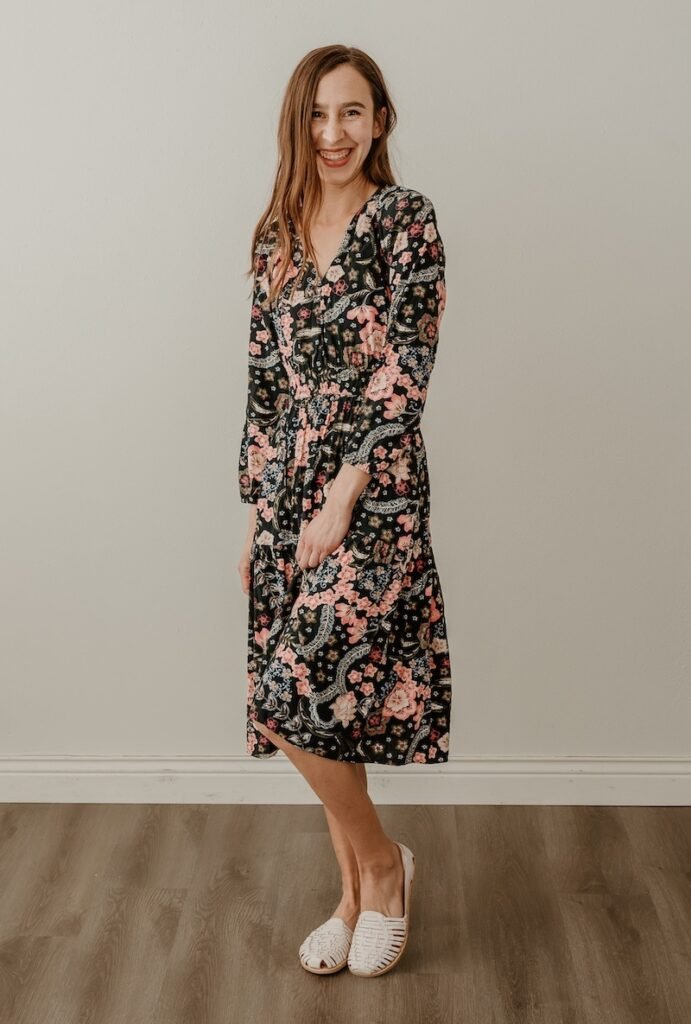 Anya standing smiling at the camera wearing a floral dress and white leather barefoot huaraches made by Orgio X Anya's Reviews