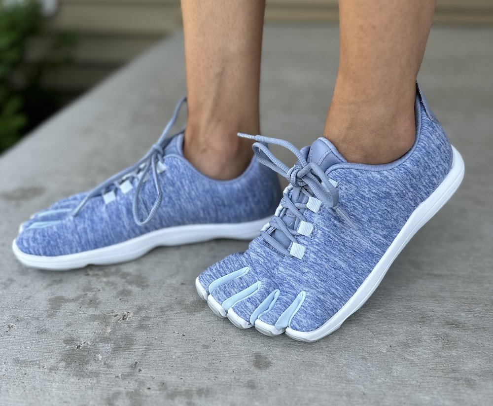 Close up of Peluva's five finger wide toe box cushioned barefoot running shoes with a blue soft knit upper and white outsole