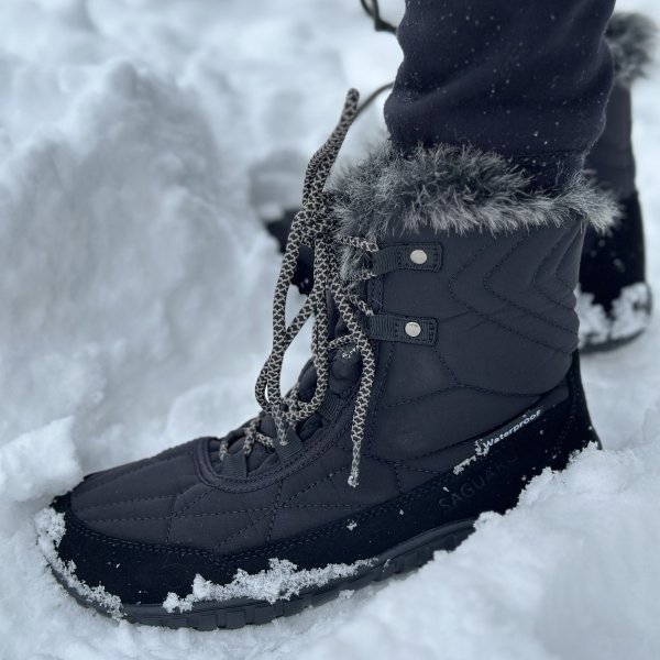 Front angled closed up of Saguaro Rise winter barefoot snow boots being worn on very snowy ground