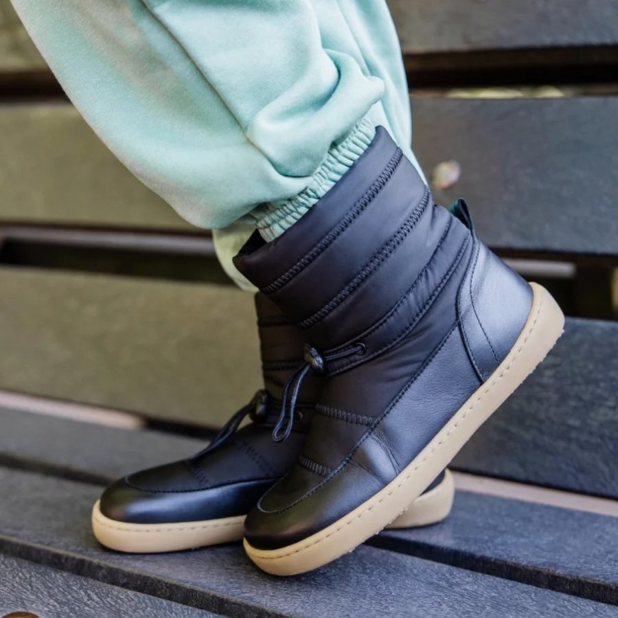 Side profile view of a pair of kids feet in Shapen Frosty barefoot winter puffer boots with a wide toe box