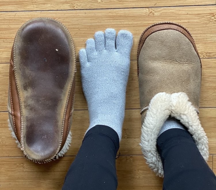 A top down view of a pair of feet standing on wood floor wearing Softstar Shoes wool sheepskin Fireside slippers in Wide width with plenty of toe space