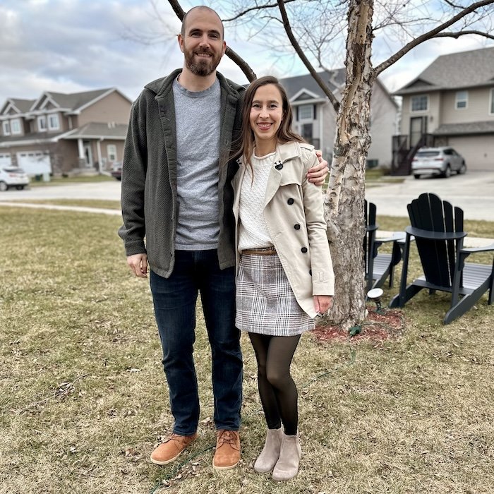 A man and woman standing side by side wearing stylish outfits and barefoot shoes - man is wearing Be Lenka Synergy in cognac and the woman is wearing Rosa boots by Anya in taupe