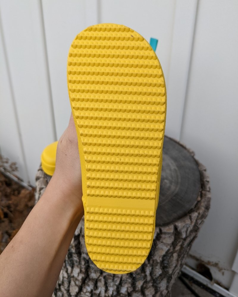 View of the outsole on a pair of Ten Little Affordable Rain Boots with grippy tread and no heel