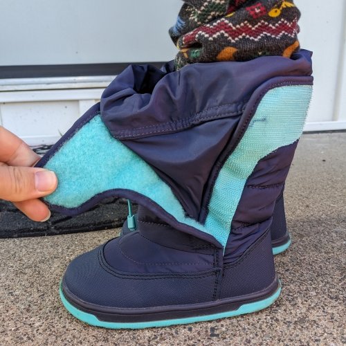 Side view of Ten Little Snow Boots with the side velcro opened to show the interior water flap. The flat zero drop sole is in the foreground