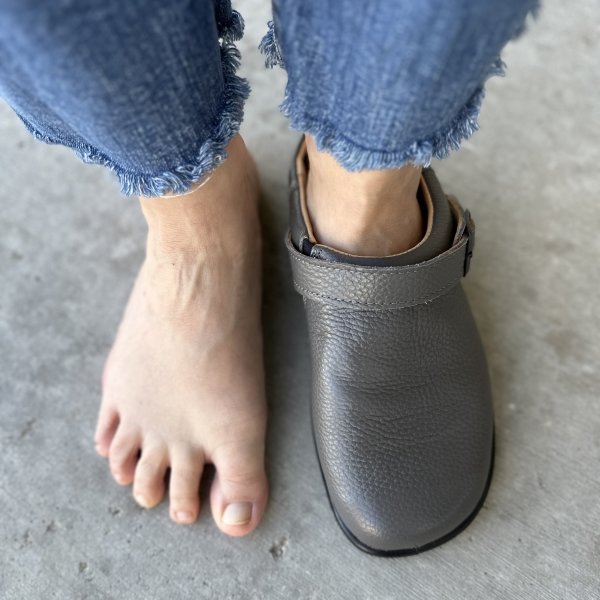 Top down close up view of a person with wide feet wearing Tomar Creation barefoot clogs on the right foot while the left foot is bare