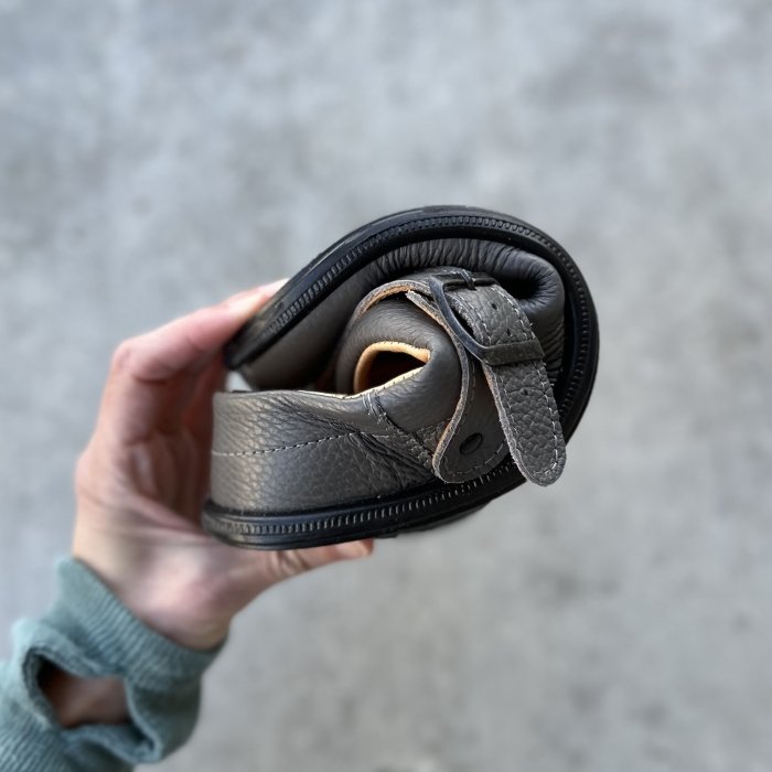 A hand showing a Tomar Creation barefoot clog squished into a tight U shape to show the flexibility of the zero drop sole