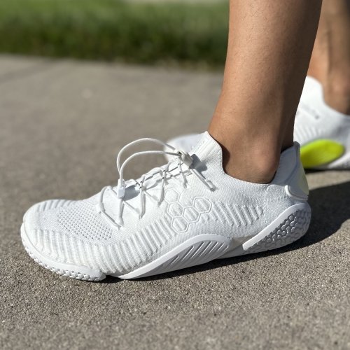 Close up side profile of Vivobarefoot Motus Flex in white, a soft stretchy barefoot shoe with a super minimal sole