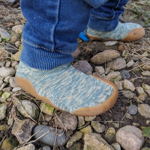 Side view of a young toddler's feet in Vivobarefoot Pluma Knit shoes with an ultra thin minimal rubber sole and stretchy upper to promote natural foot function