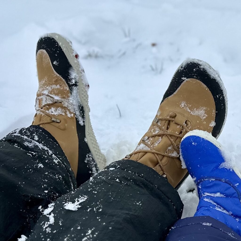 a close up of a pair of feet resting in snow wearing Vivobarefoot Tracker Winter in Acorn