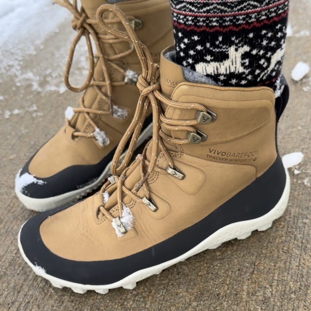 A pair of feet standing on concrete wearing barefoot snow boots from Vivobarefoot - the Tracker Winter