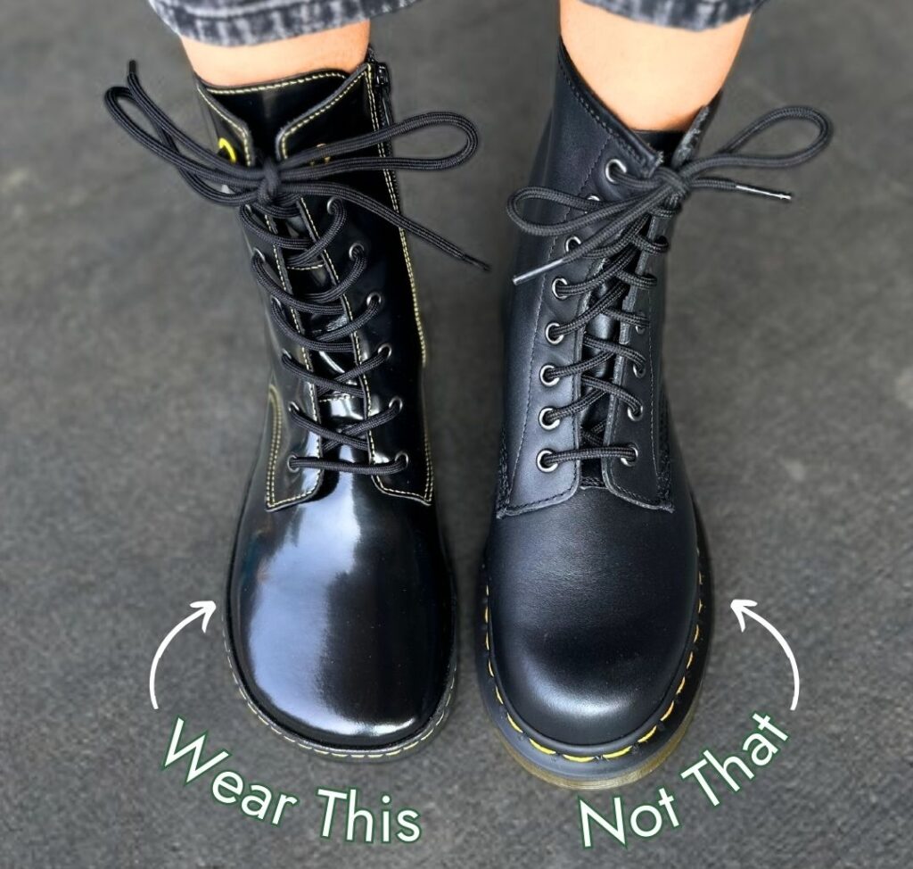 A top down close up of a person's feet wearing black lace up combat boots. On the left is a Shapen Barefoot wide toe box Maverick boot with the text "Wear This" and on the right is a Doc Marten with the text "Not That" because it has a narrow tapered toe box
